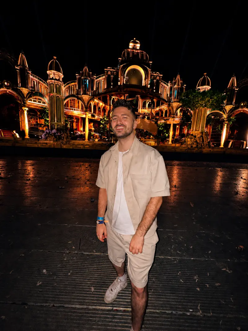 Yohann Warren smiling at night in front of the illuminated Great Library stage at Tomorrowland